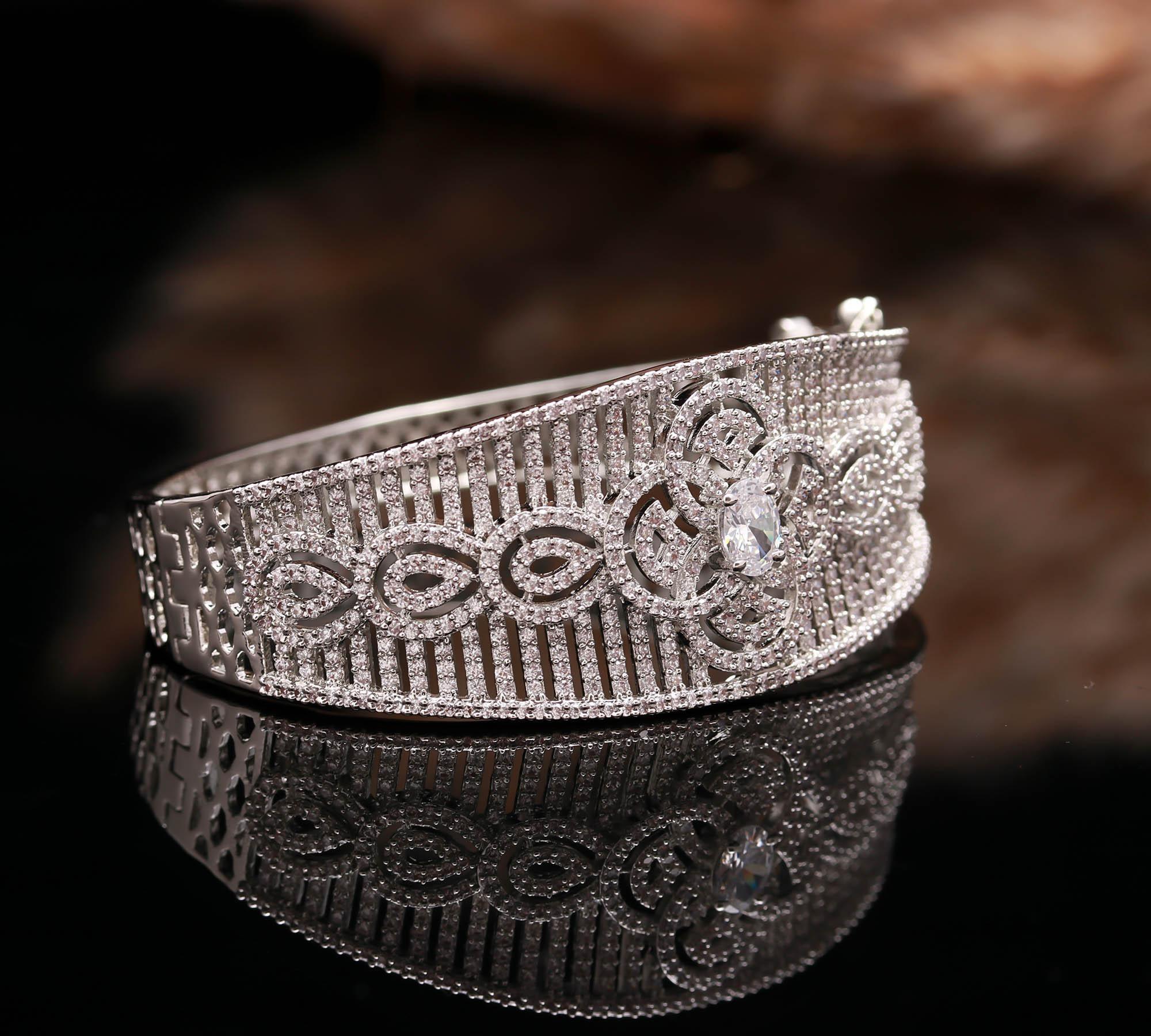 Intricate silver bracelet with floral and geometric diamond patterns on reflective black surface
