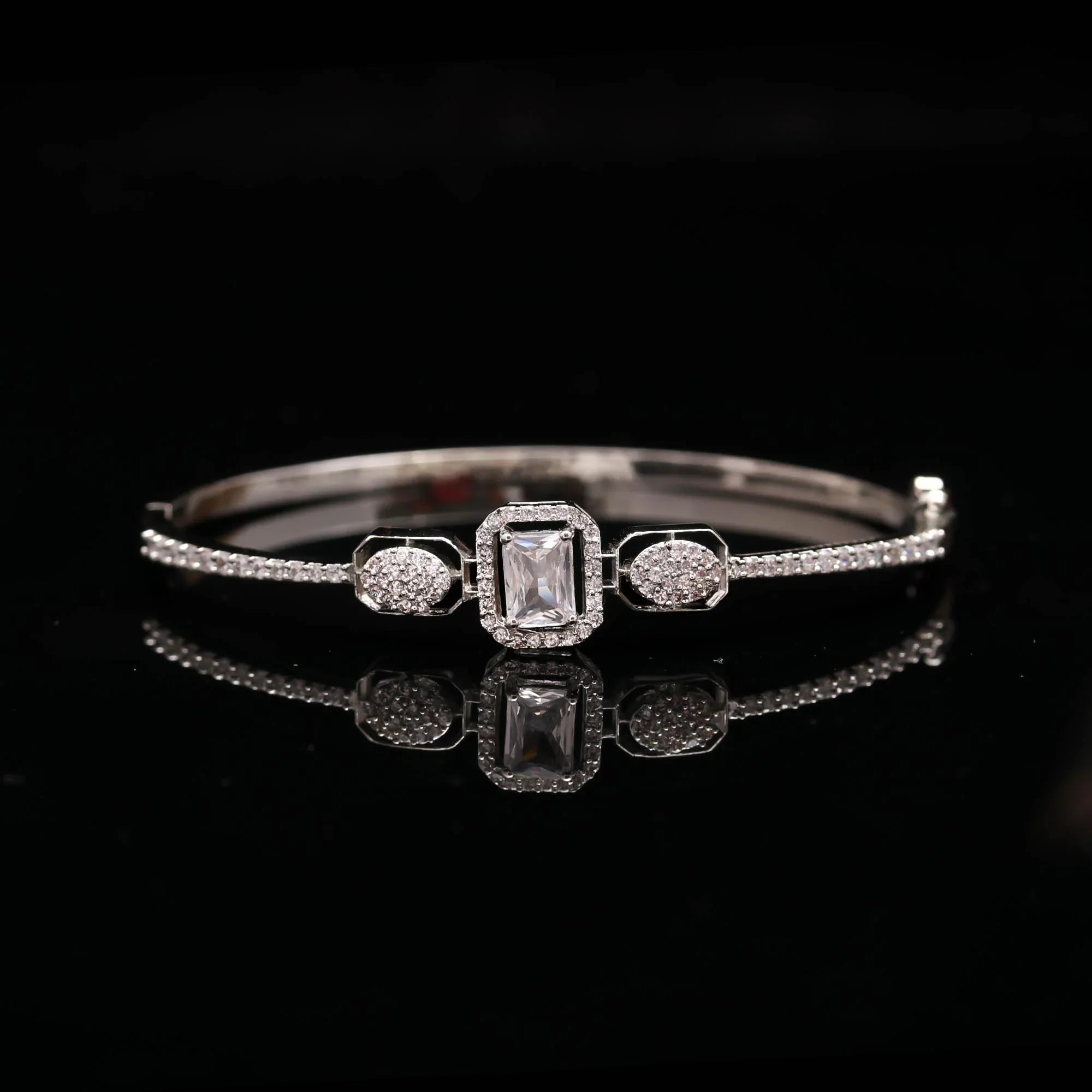 Elegant silver bracelet with central rectangular clear gemstone and surrounding small diamonds on black background