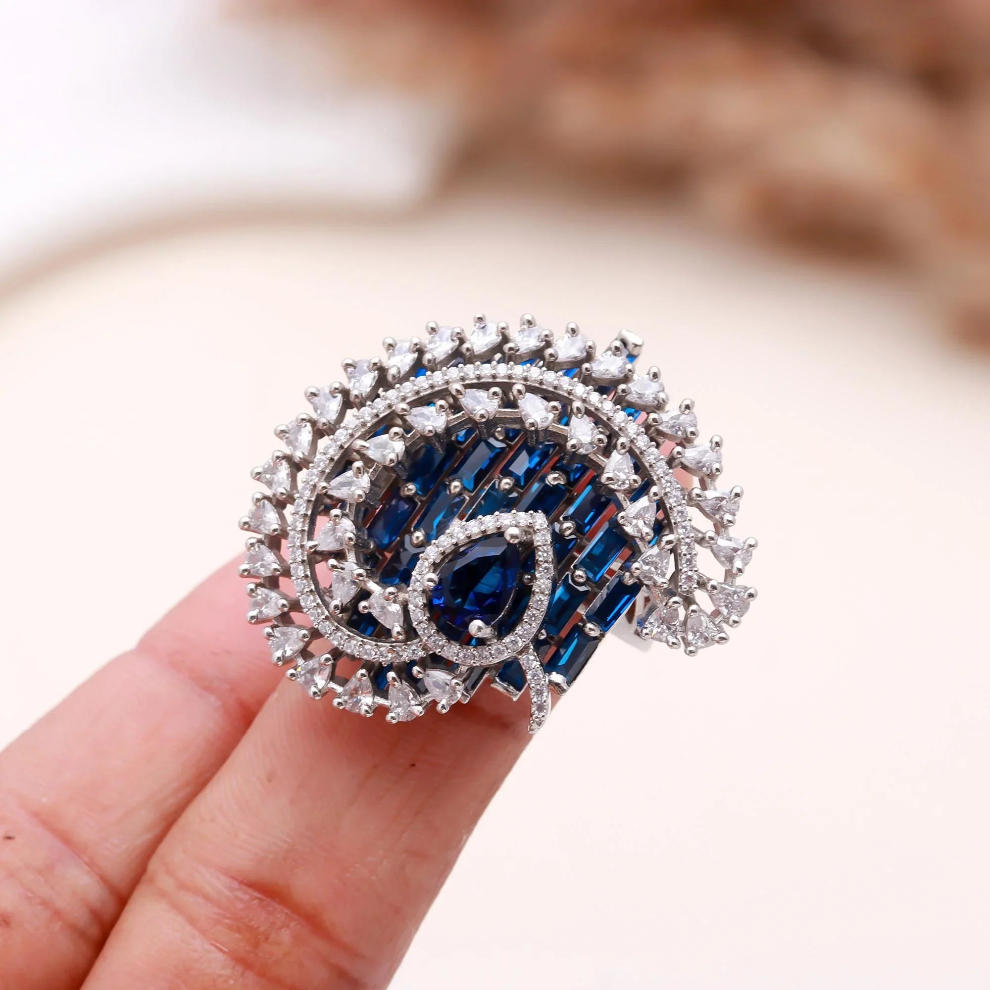 Haamsi blue sapphire and white diamond swirl cocktail ring held on finger