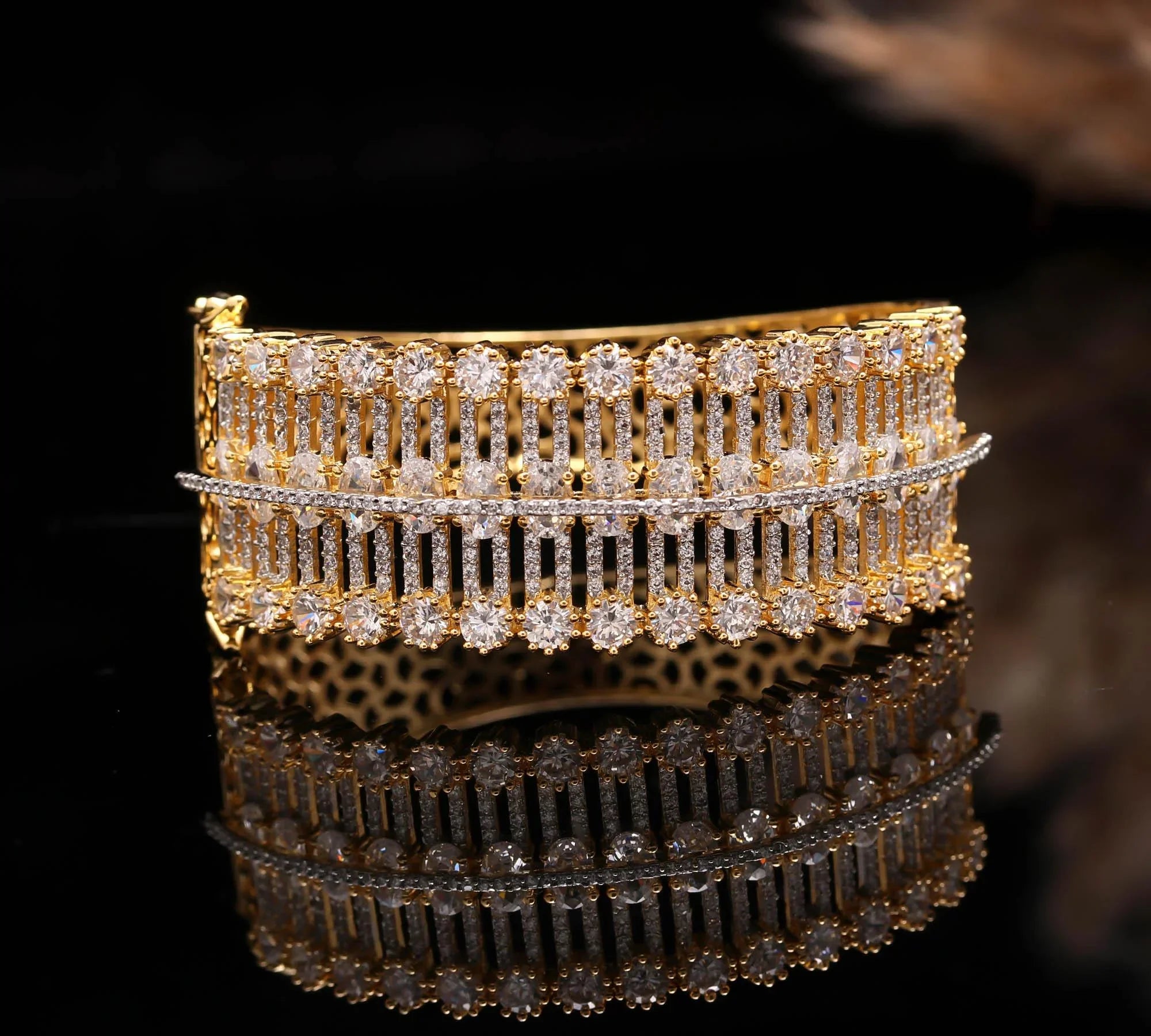 Elegant gold bracelet with multiple rows of sparkling clear crystals on black reflective surface