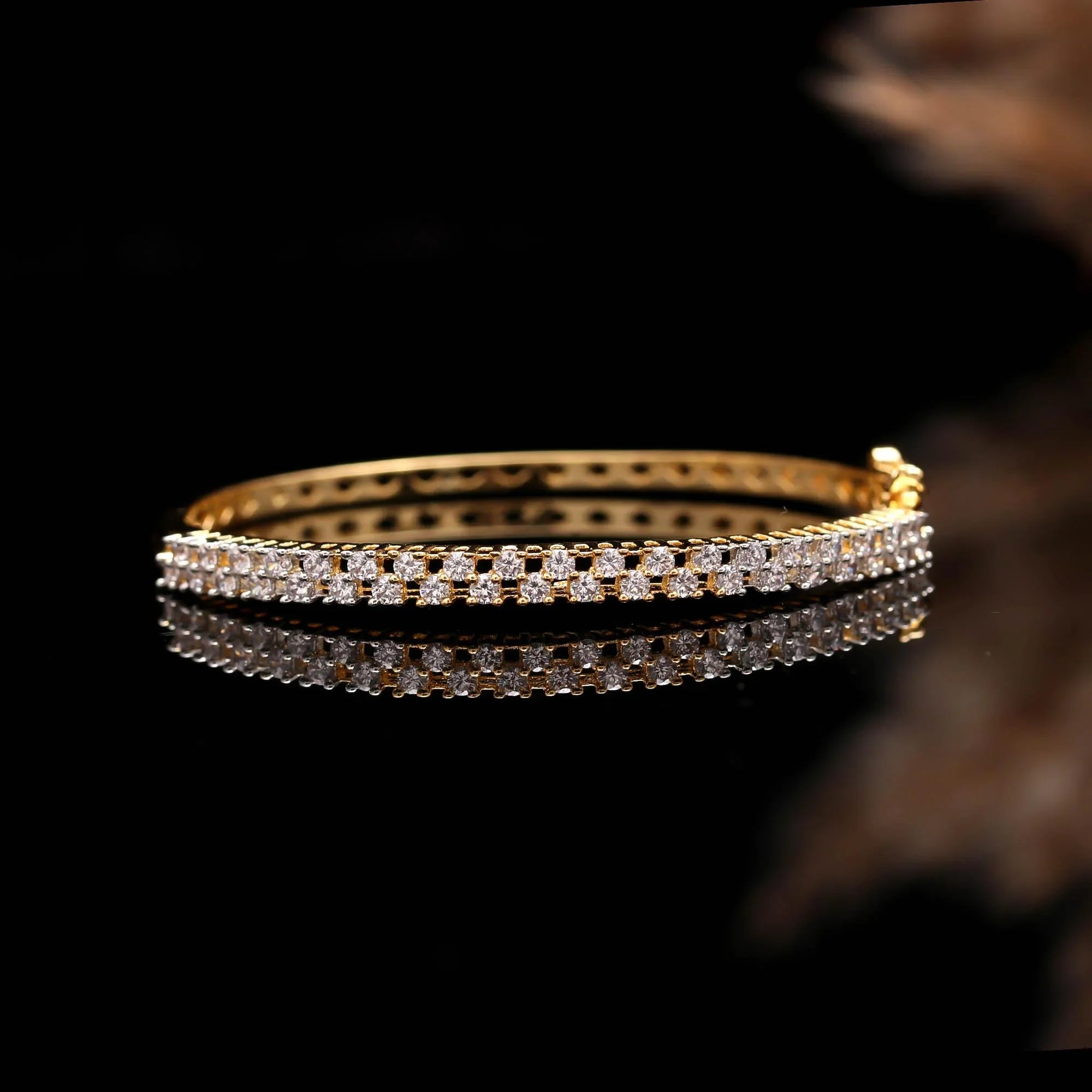 Elegant gold bangle bracelet with two rows of sparkling white diamonds on black reflective surface