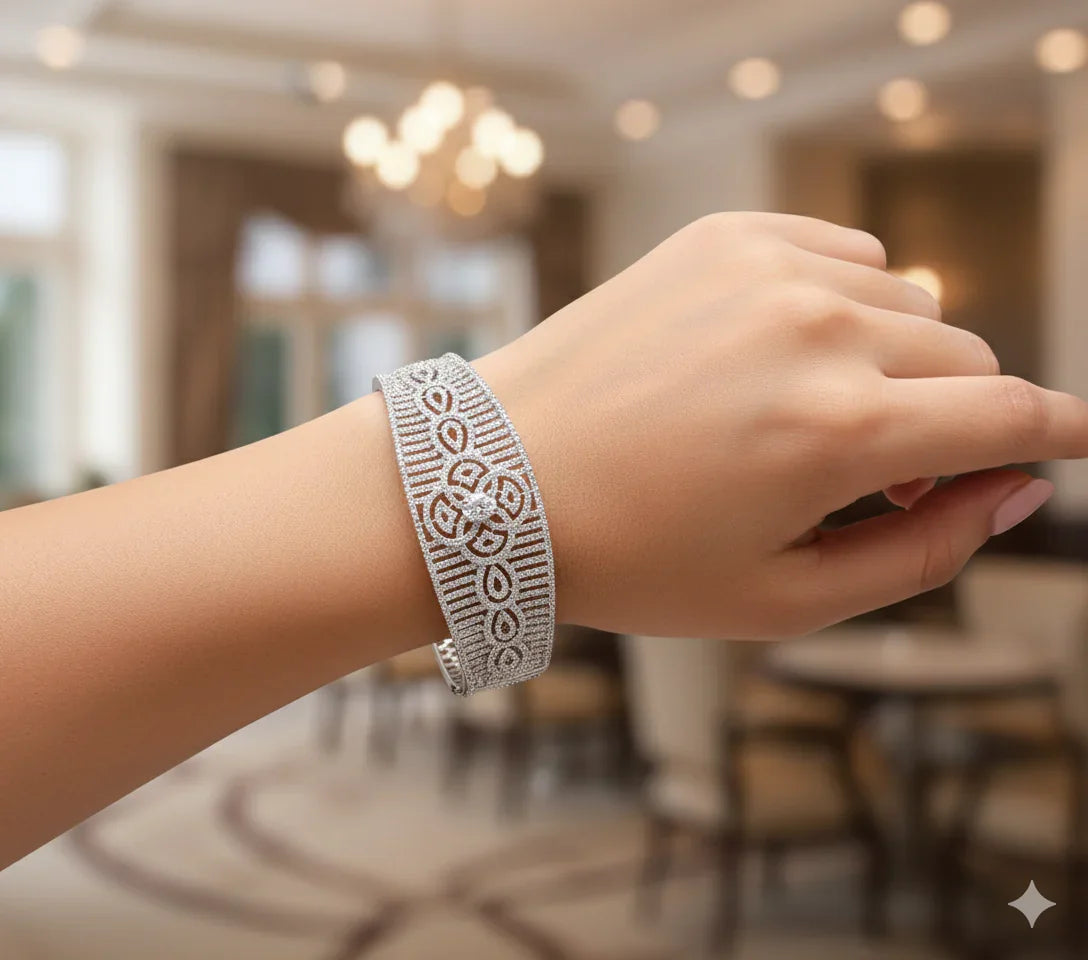 Elegant silver bracelet with intricate floral and geometric patterns on wrist in a blurred indoor setting
